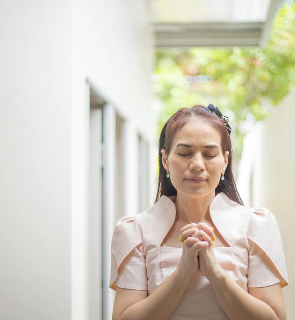 Person meditating peacefully outdoors with nature background.